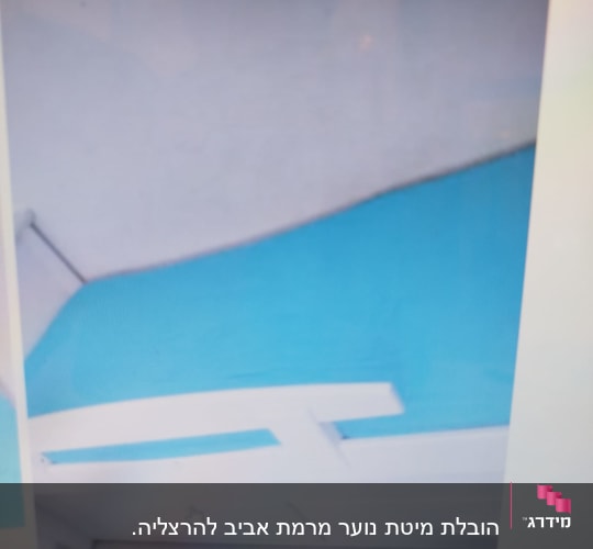 מיטה עם מצעים כחולים ומעקה לבן